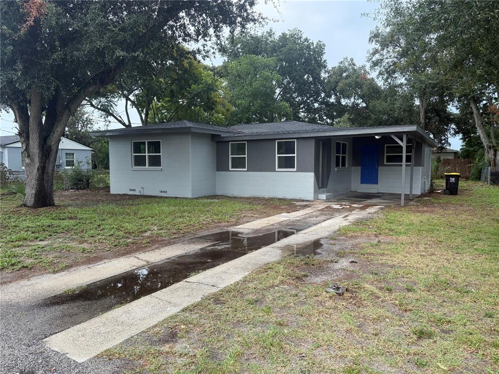 A single-story house with a gray exterior, a blue front door, and a concrete driveway — 309 1ST STREET, AUBURNDALE, FL