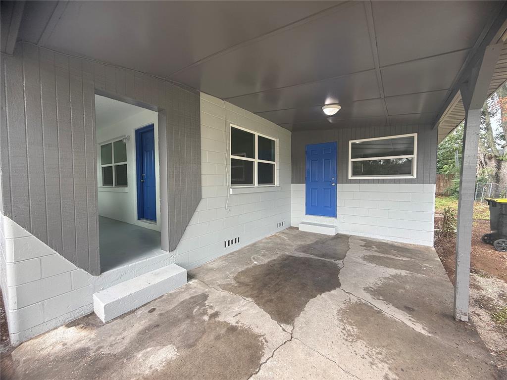 A concrete patio area features a covered entryway with two blue doors and gray walls — 309 1ST STREET, AUBURNDALE, FL