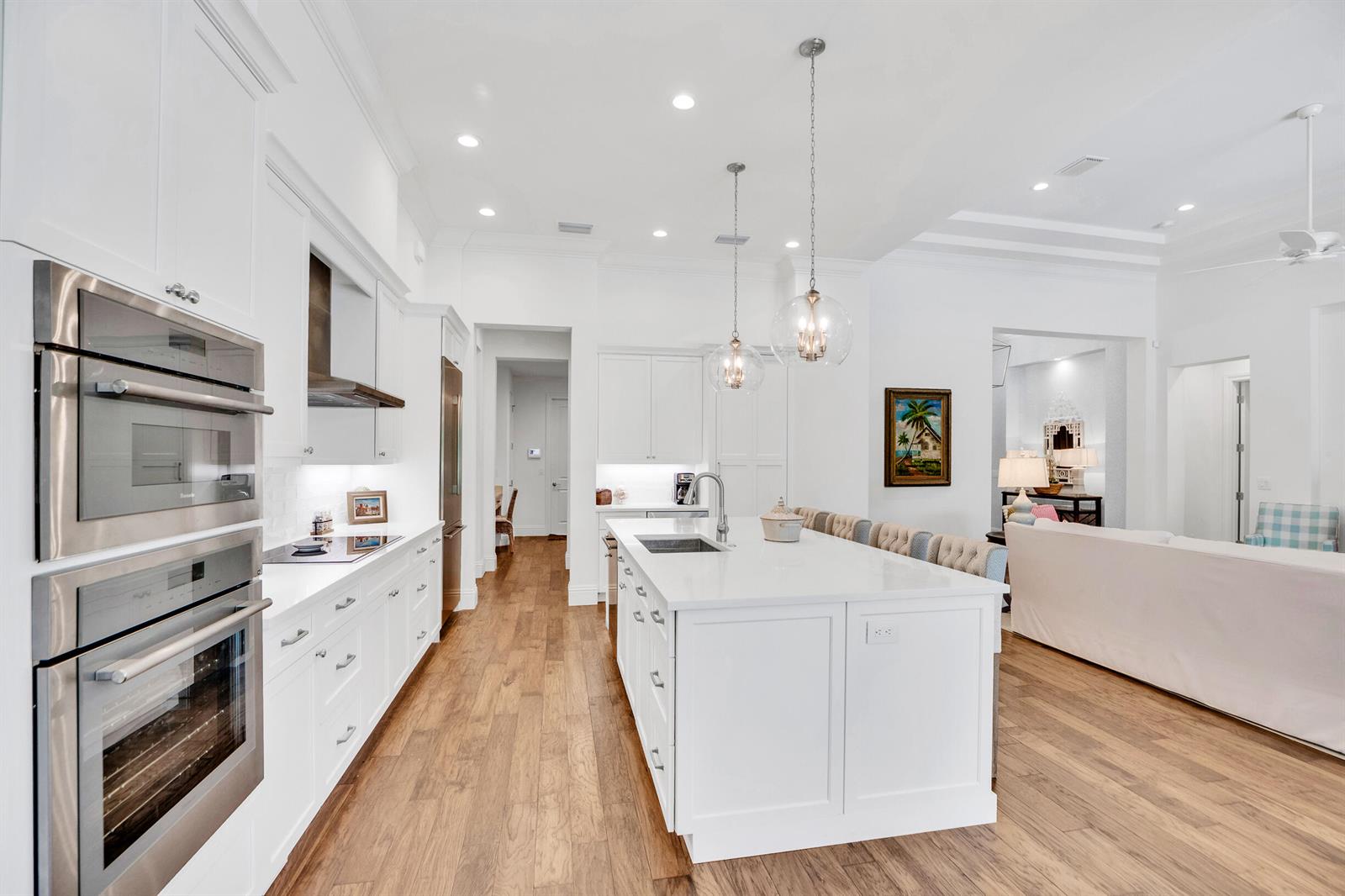 A bright white kitchen features a large center island, stainless steel appliances, and hardwood floors — VERO BEACH, FL