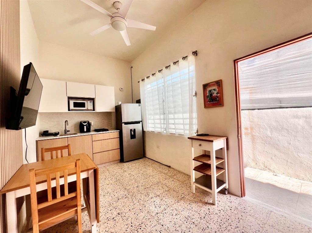 A small kitchen features light wood cabinets, a stainless steel refrigerator, and a dining table — 119 STA CECILIA, SAN JUAN, PR