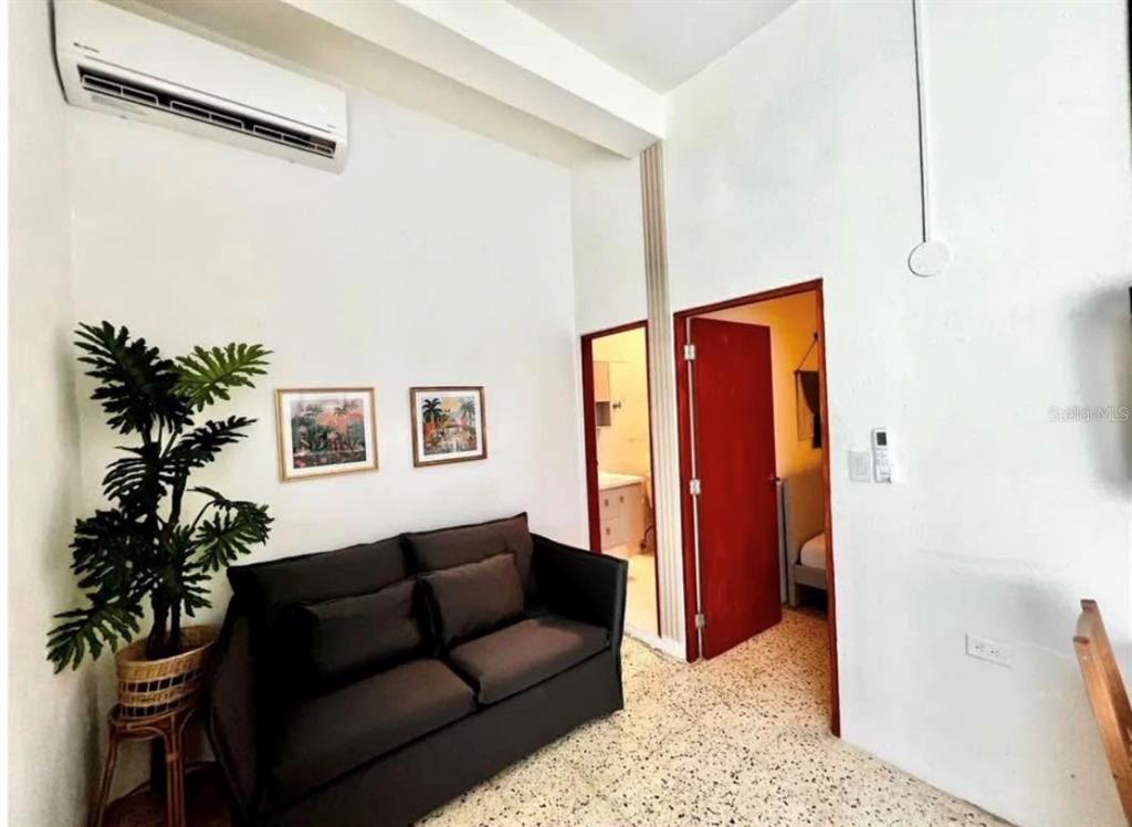 A living room features a dark sofa, a potted plant, and two doorways on terrazzo flooring — 119 STA CECILIA, SAN JUAN, PR