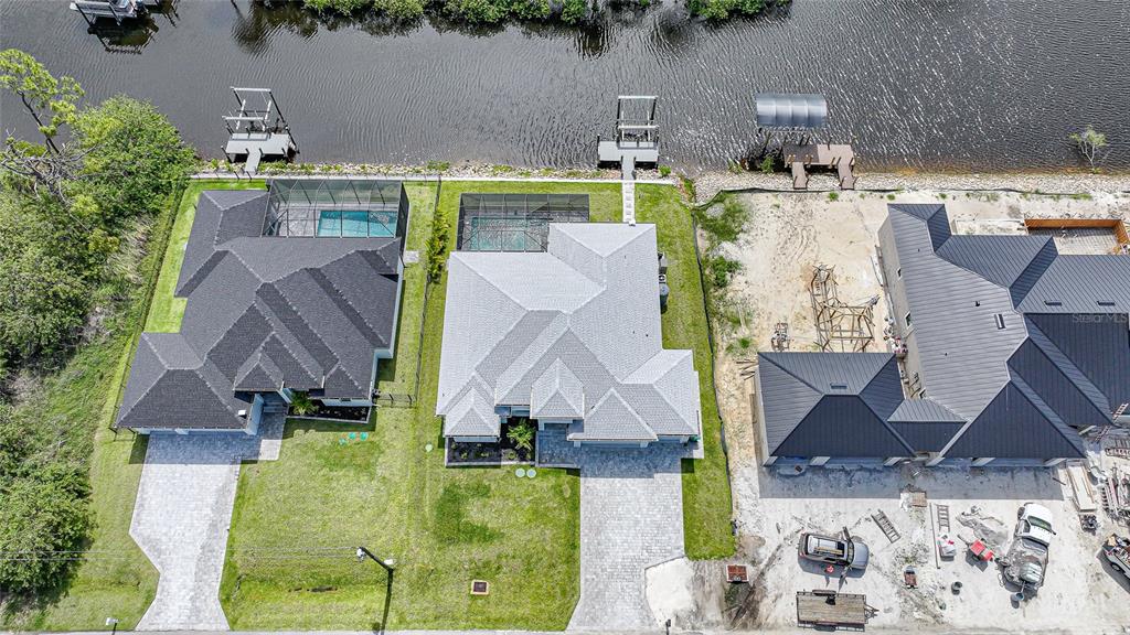 An aerial view shows three waterfront houses with pools and docks along a canal — 1411 LIGGETT CIRCLE, PORT CHARLOTTE, FL