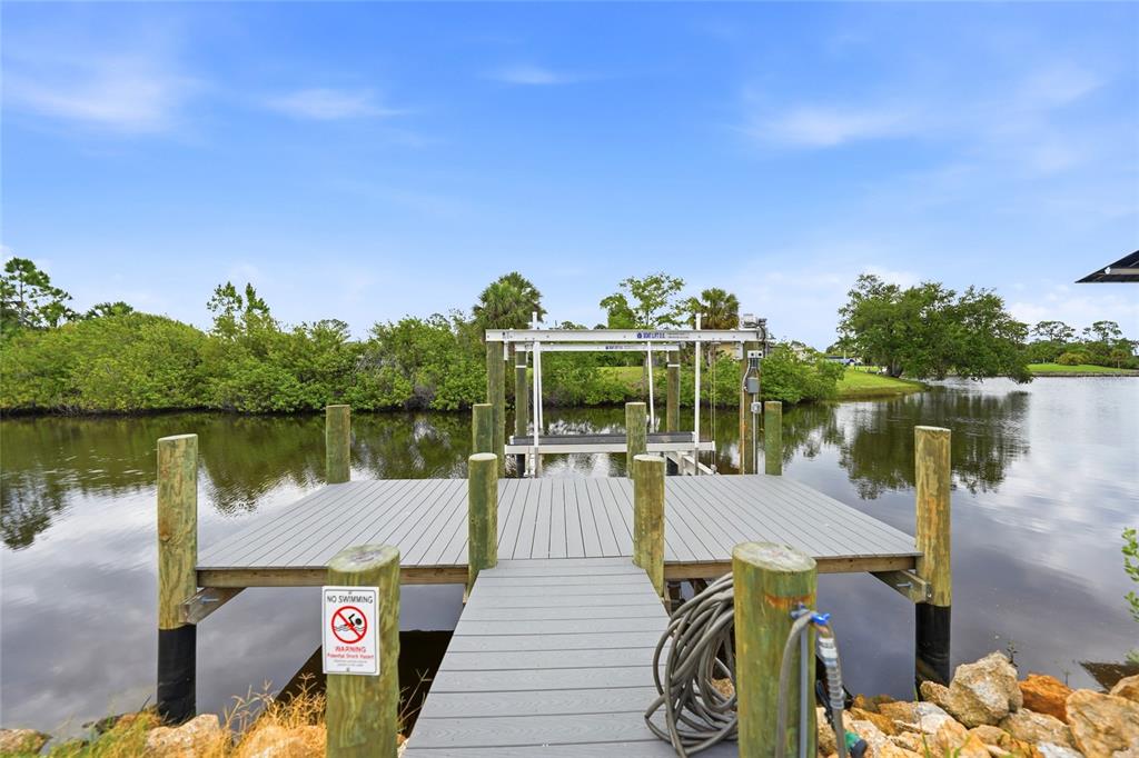 A gray composite dock with a boat lift extends over a calm body of water — 1411 LIGGETT CIRCLE, PORT CHARLOTTE, FL