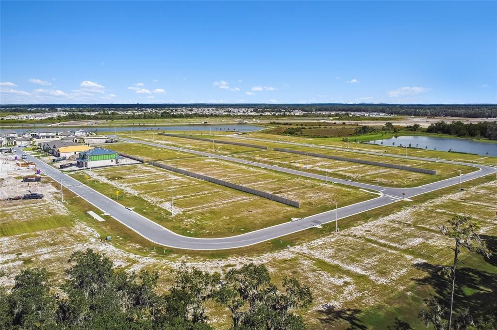 An aerial view shows a residential development with paved roads and several vacant building lots — 5800 FREESIA DRIVE, LAKELAND, FL