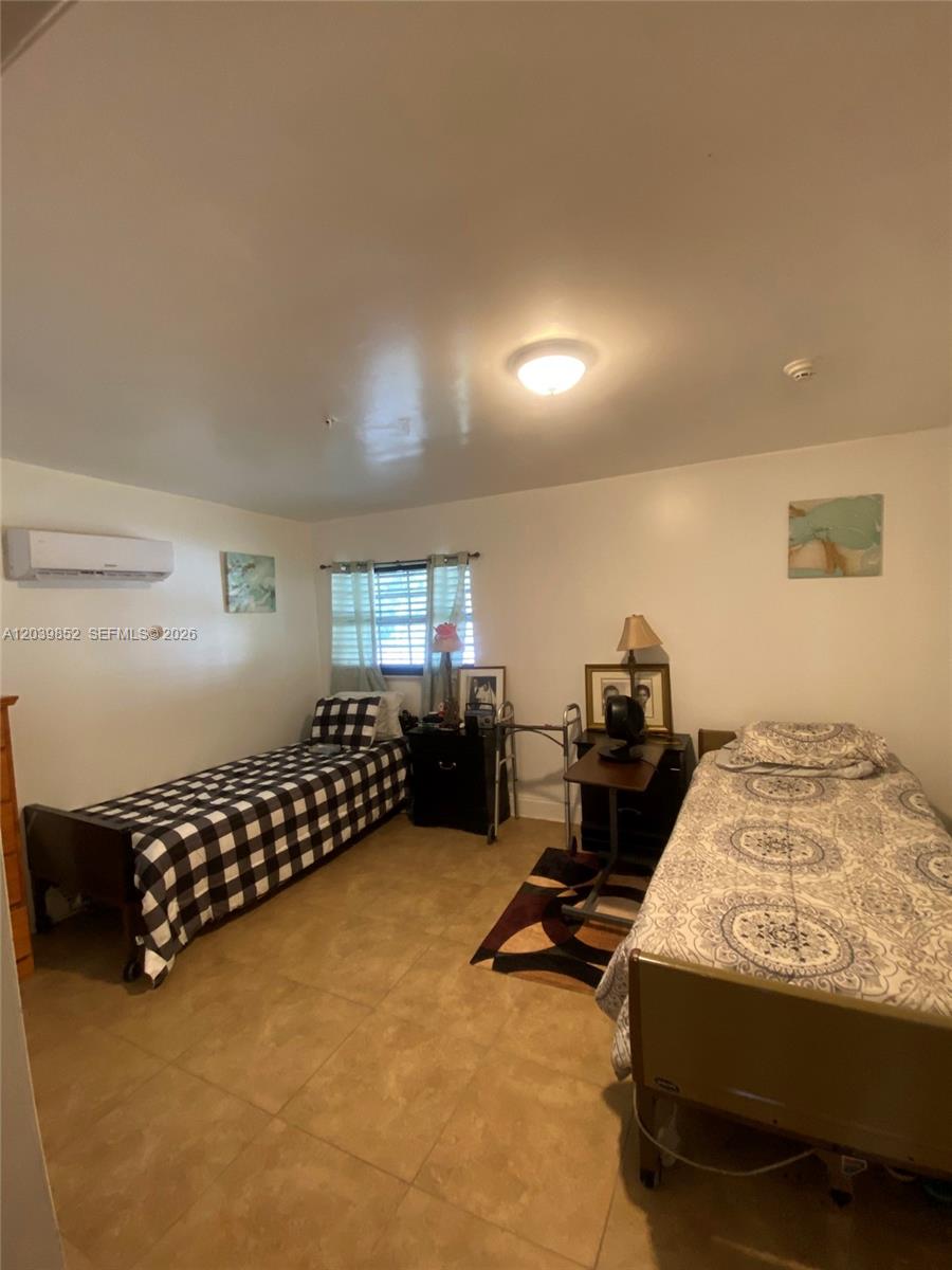 A bedroom features two twin beds, tile flooring, and a wall-mounted air conditioning unit — MARGATE, FL