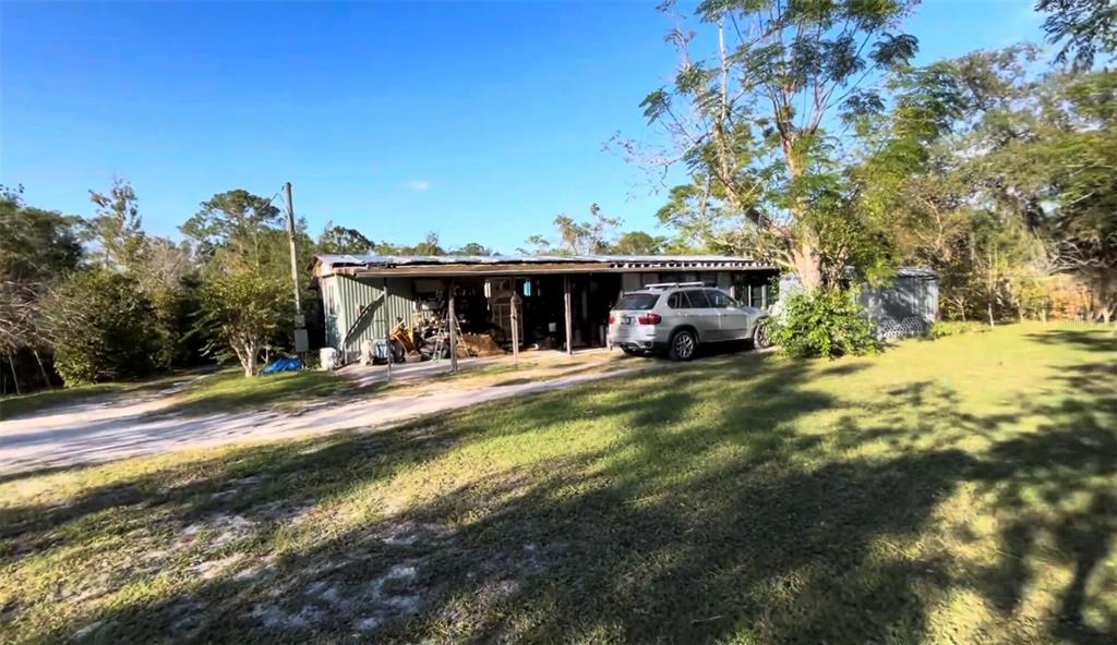 A single-story house with a covered porch and a silver SUV parked in the yard — 31304 HILLSIDE DRIVE, DELAND, FL