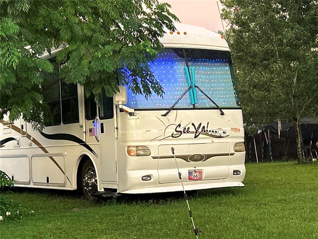 A white Alfa motorhome with a blue light display on the windshield parked on grass — 31304 HILLSIDE DRIVE, DELAND, FL