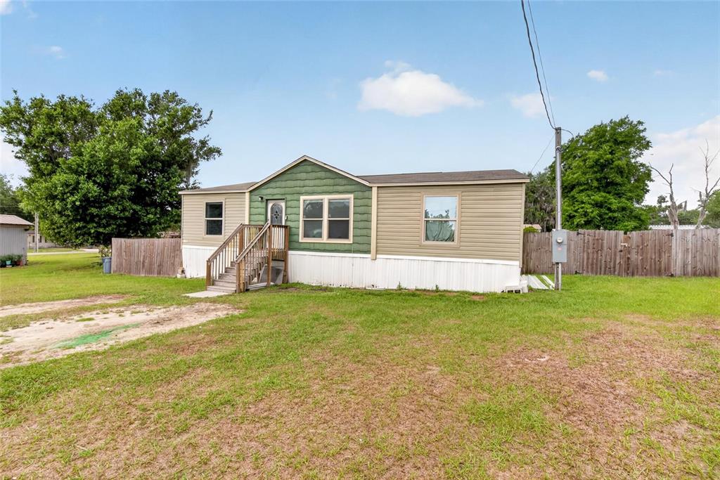 A single-story manufactured home with tan siding, a green accent wall, and wooden front stairs — 3991 SHADY COURT, MULBERRY, FL