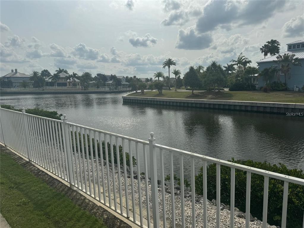 A white metal fence overlooks a canal with houses and palm trees in the background — 5714 TIDES PLACE, APOLLO BEACH, FL