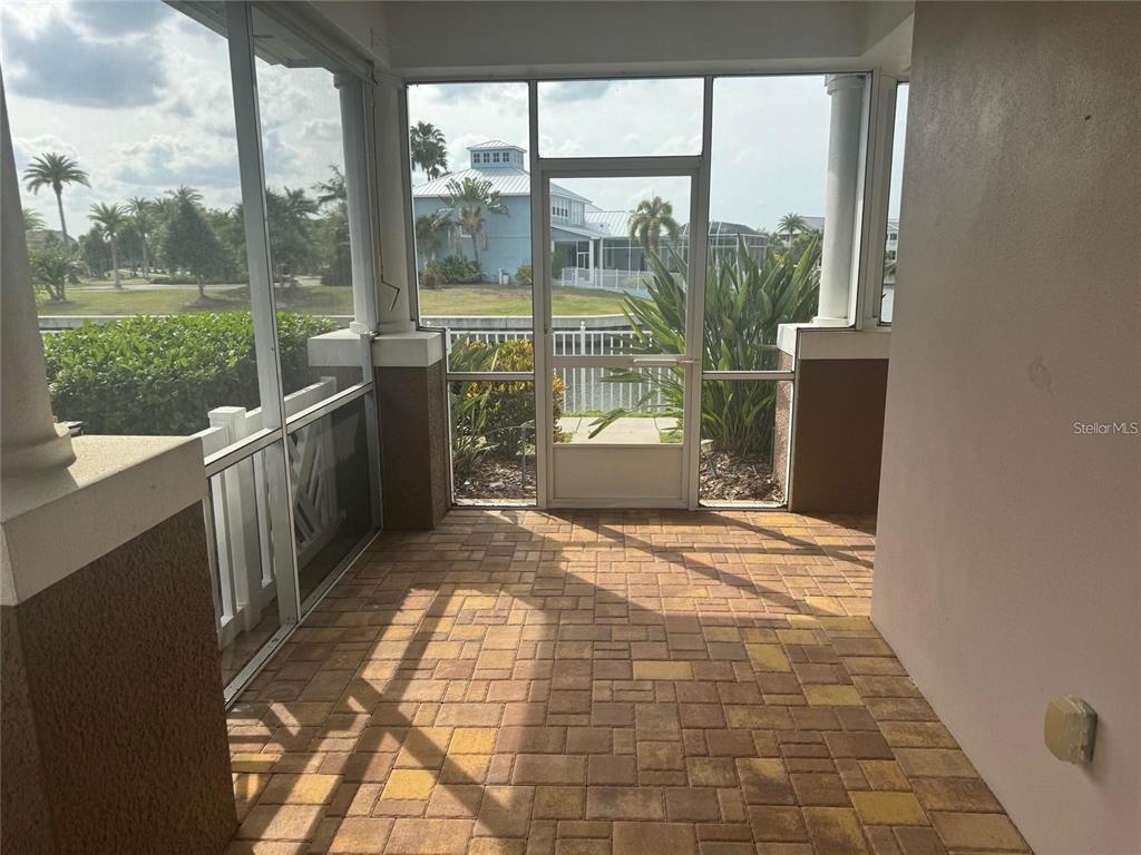 A screened-in patio features paver flooring, a screen door, and a view of a canal — 5714 TIDES PLACE, APOLLO BEACH, FL