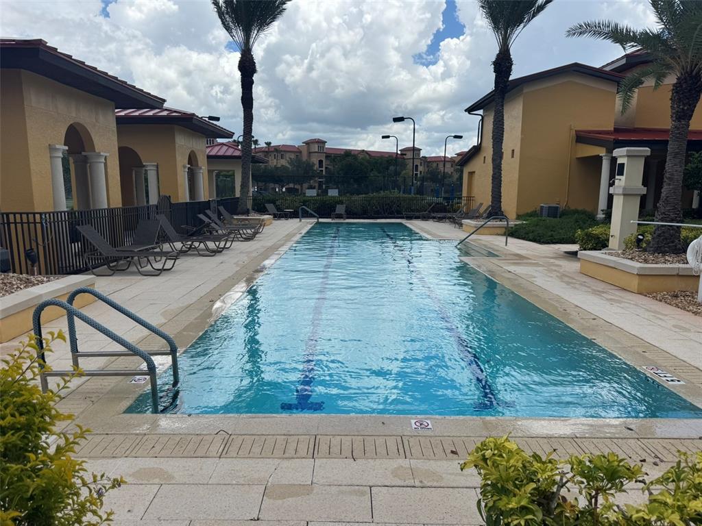 A rectangular lap pool is surrounded by a paved deck, lounge chairs, and palm trees — 99 VIVANTE BOULEVARD UNIT 415, PUNTA GORDA, FL