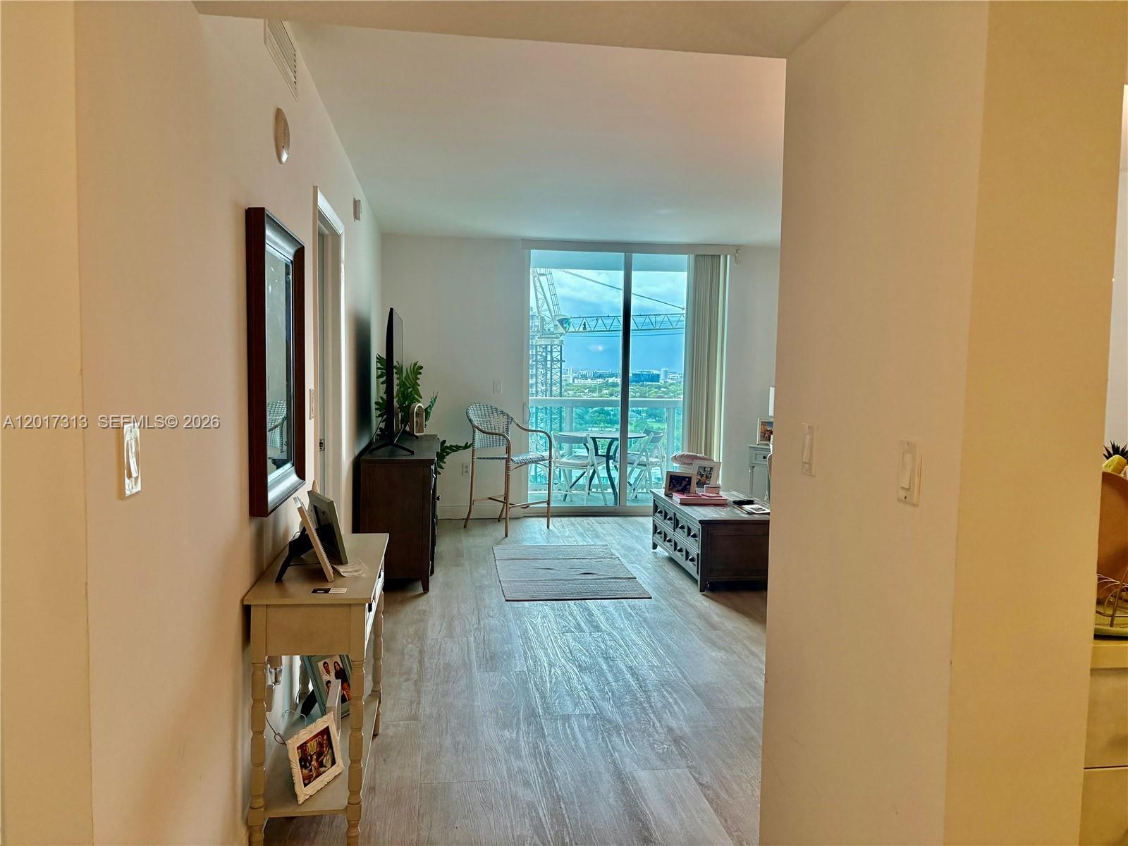 A living room features wood-look flooring, a balcony with city views, and a console table — 1800 N Bayshore Dr # 1704, Miami FL 33132, MIAMI, FL