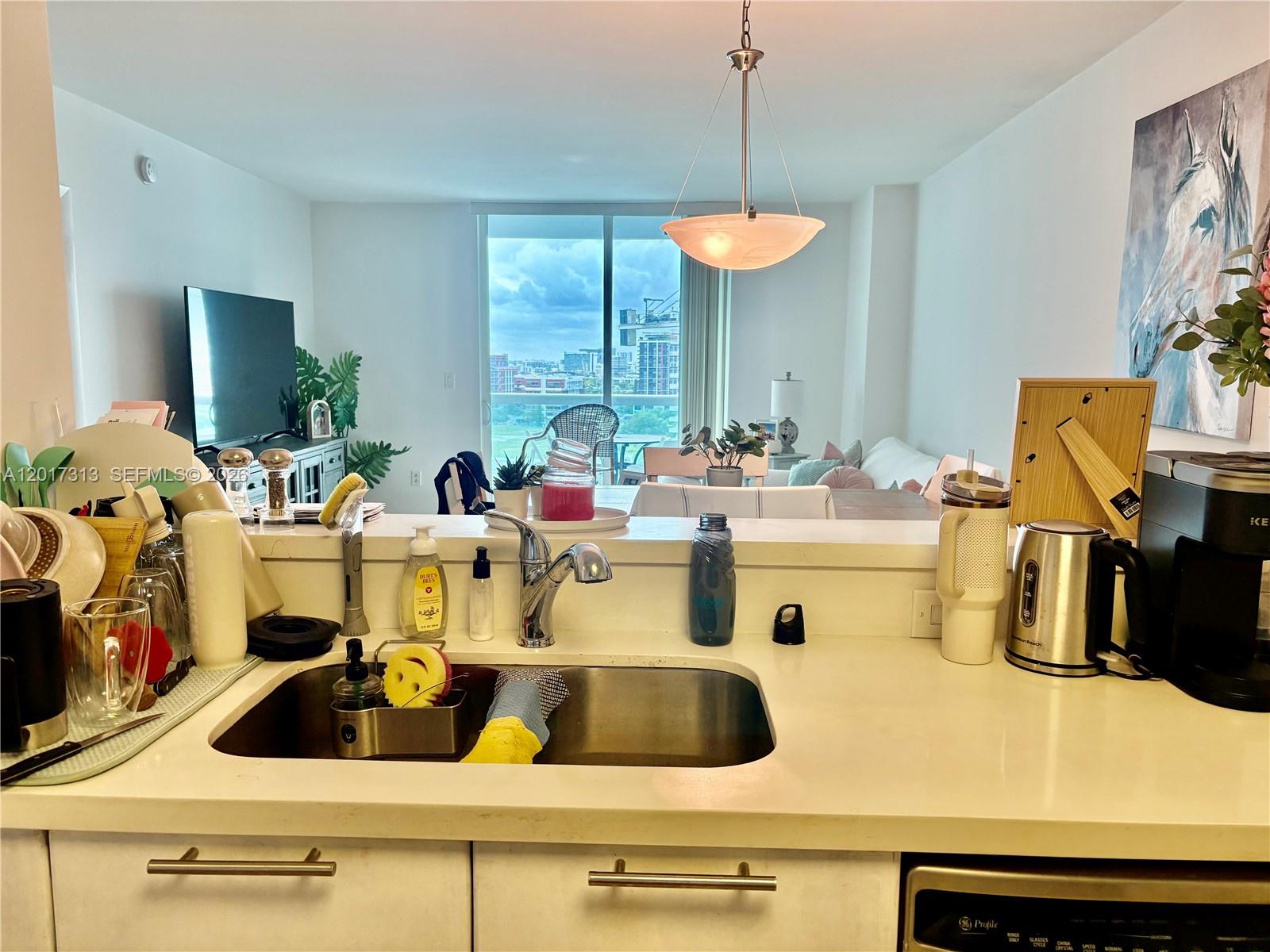 A kitchen sink and counter overlook a living area with a balcony and city view — 1800 N Bayshore Dr # 1704, Miami FL 33132, MIAMI, FL