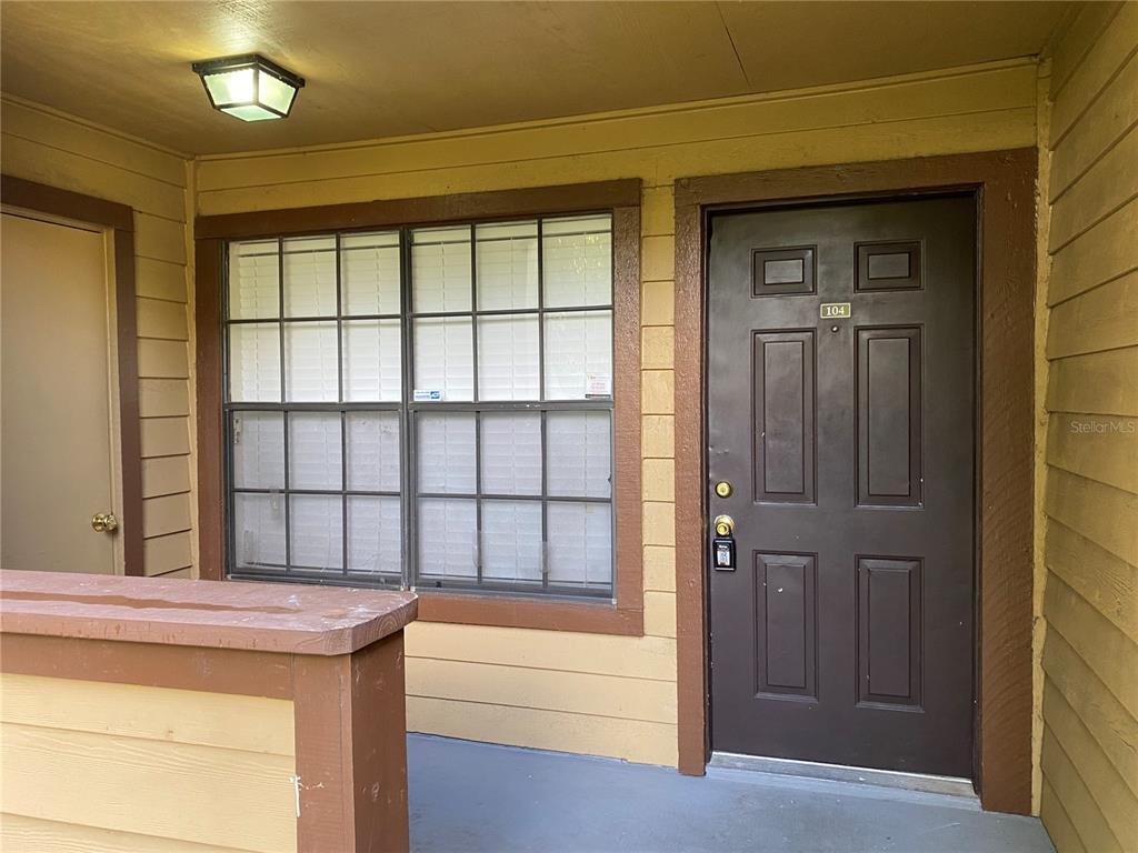 An exterior view of a residential apartment entrance with a brown door and window — 400 LAKE PLACID COURT UNIT 104, ALTAMONTE SPRINGS, FL
