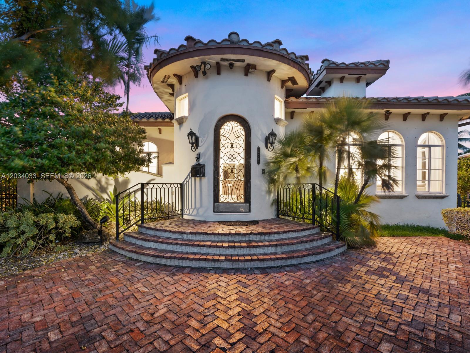 The exterior of a white Mediterranean-style house features a circular entryway with a brick staircase — 1223 Jackson St, Hollywood FL 33019, HOLLYWOOD, FL