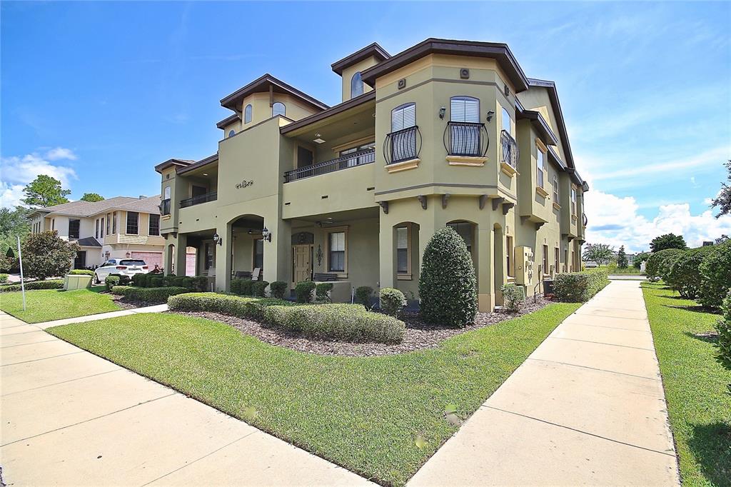 A multi-story tan apartment building with a corner turret and a sidewalk in the foreground — 1401 TOWN PLAZA COURT UNIT 1020, WINTER SPRINGS, FL