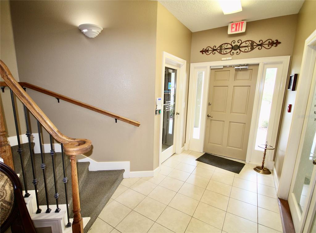 An interior entryway features a carpeted staircase with a wooden railing and a tiled floor — 1401 TOWN PLAZA COURT UNIT 1020, WINTER SPRINGS, FL