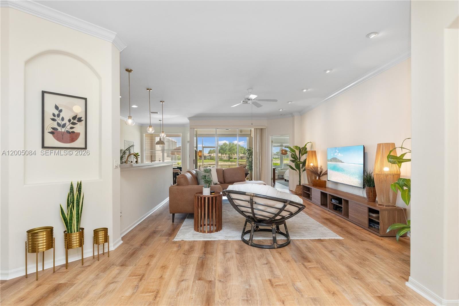 A living room features wood-look flooring, a brown sectional sofa, and a view of water — 1896 Crestview Way, Naples FL 34119, NAPLES, FL