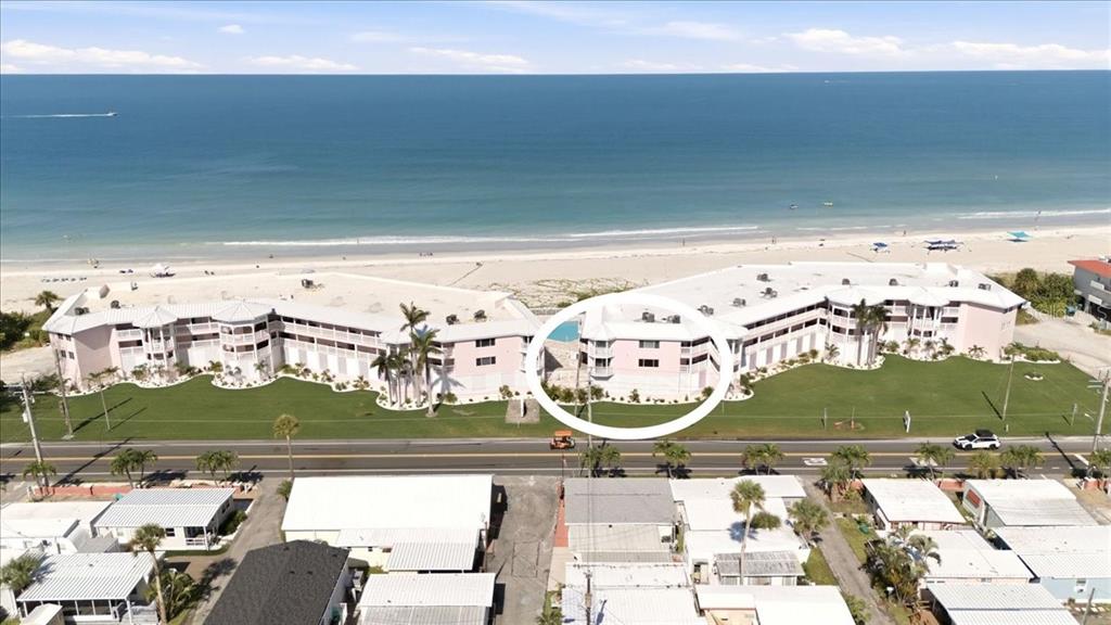 An aerial view shows a pink beachfront condominium complex with a circled central entrance area — 2600 GULF DRIVE N UNIT 30, BRADENTON BEACH, FL