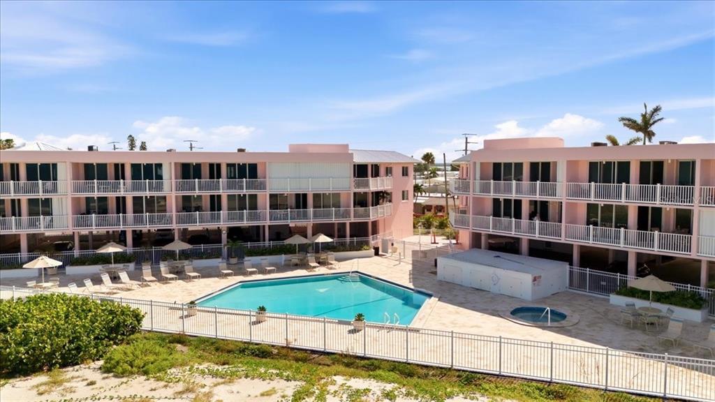 An exterior view of a pink multi-story apartment complex with a swimming pool and patio — 2600 GULF DRIVE N UNIT 30, BRADENTON BEACH, FL
