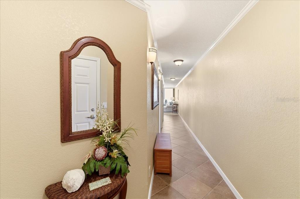 A hallway with tile flooring leads toward a living area past a mirror and table — 2600 GULF DRIVE N UNIT 30, BRADENTON BEACH, FL