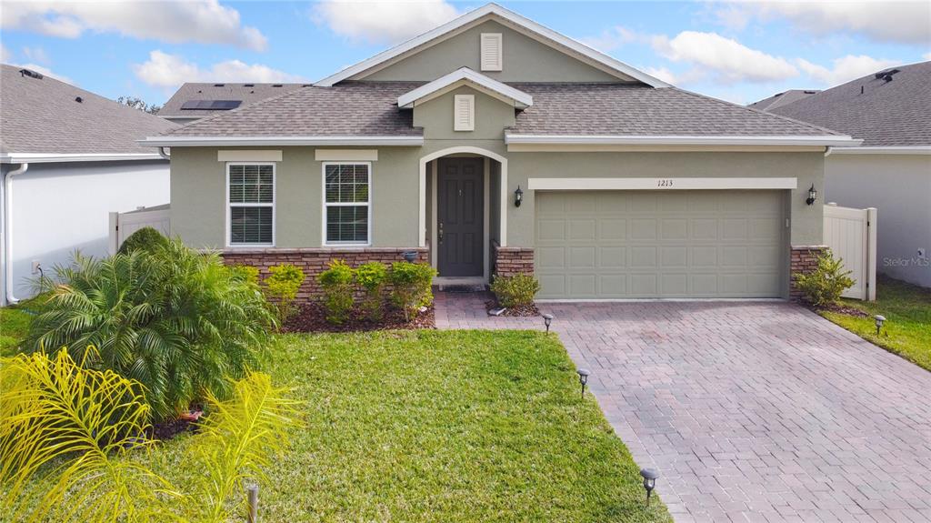 A single-story house with a paved driveway, stone accents, and a two-car garage — 1213 CRANE TALON WAY, SANFORD, FL