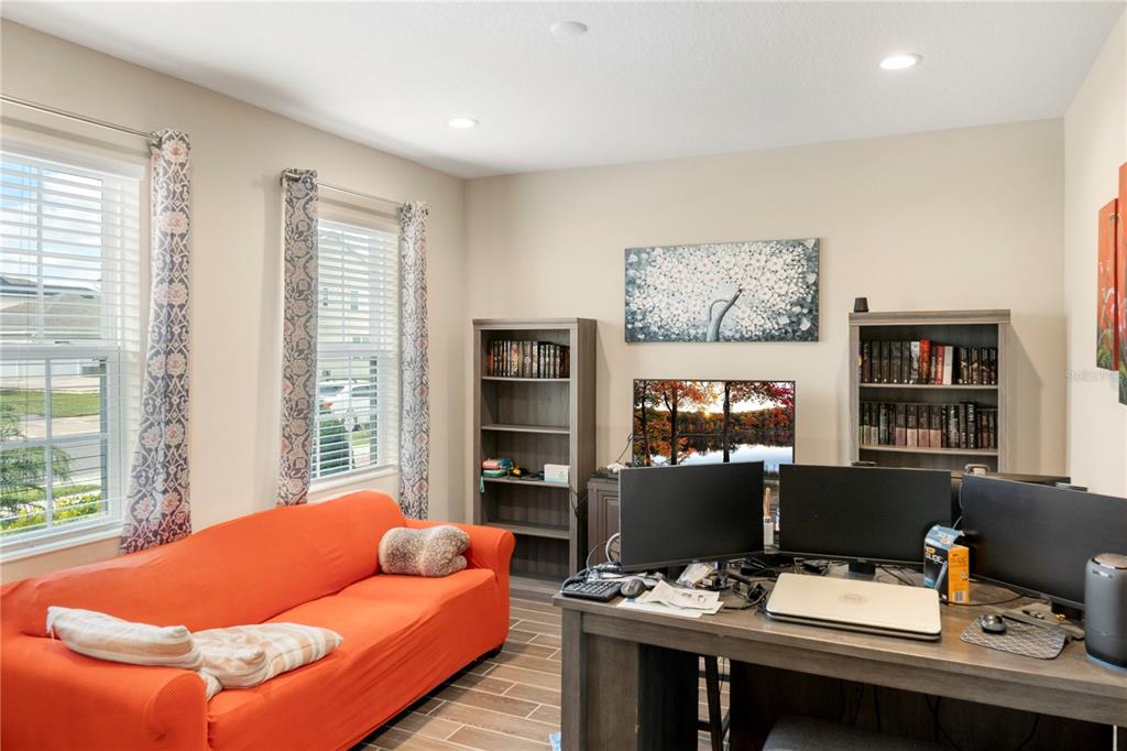 A home office features an orange sofa, two bookshelves, a desk with monitors, and two windows — 1213 CRANE TALON WAY, SANFORD, FL