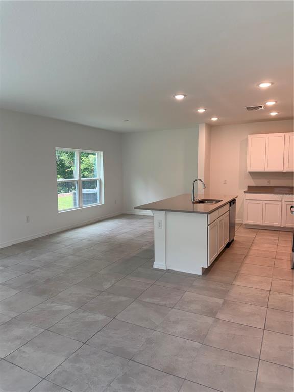A kitchen features white cabinets, a central island with a sink, and light-colored tile flooring — 1113 MAJESTY PALM CIRCLE, DELAND, FL