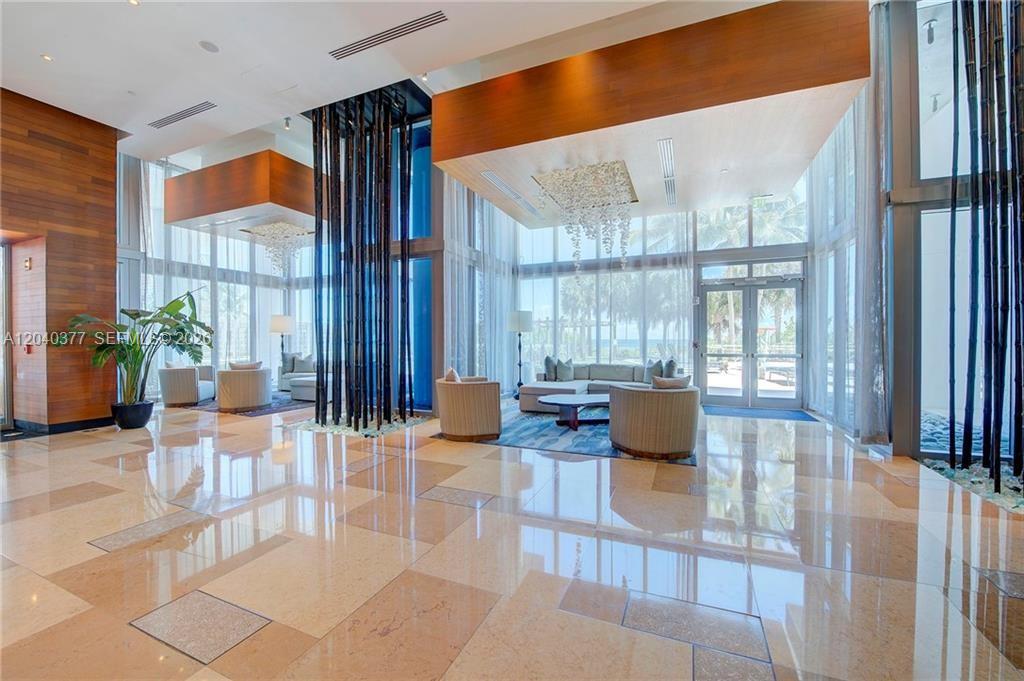 A bright, modern lobby features high ceilings, floor-to-ceiling windows, polished tile floors, and decorative pillars — 6899 Collins Ave # 2208, Miami Beach FL 33141, MIAMI BEACH, FL