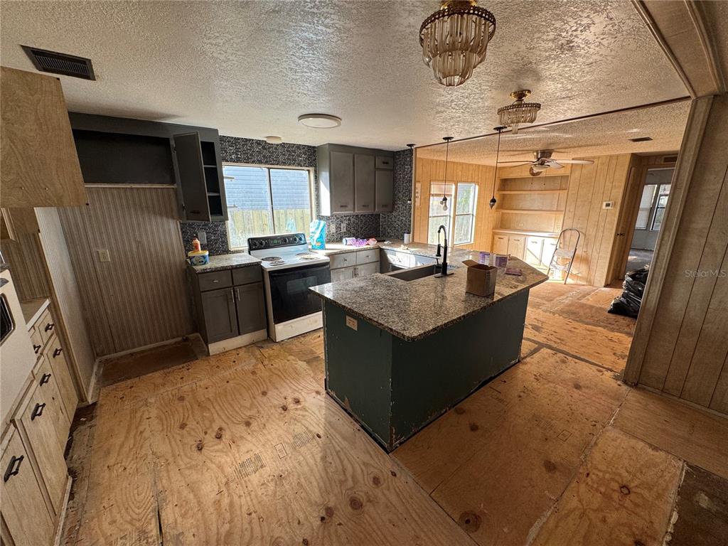 A kitchen with gray cabinets, granite countertops, an island, and unfinished plywood flooring — 10559 BAY HILLS CIRCLE, THONOTOSASSA, FL