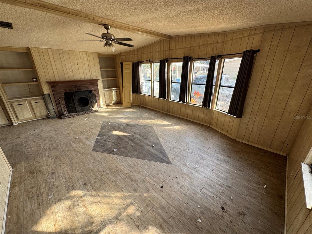 A living room features wood-paneled walls, a brick fireplace, and a ceiling fan — 10559 BAY HILLS CIRCLE, THONOTOSASSA, FL