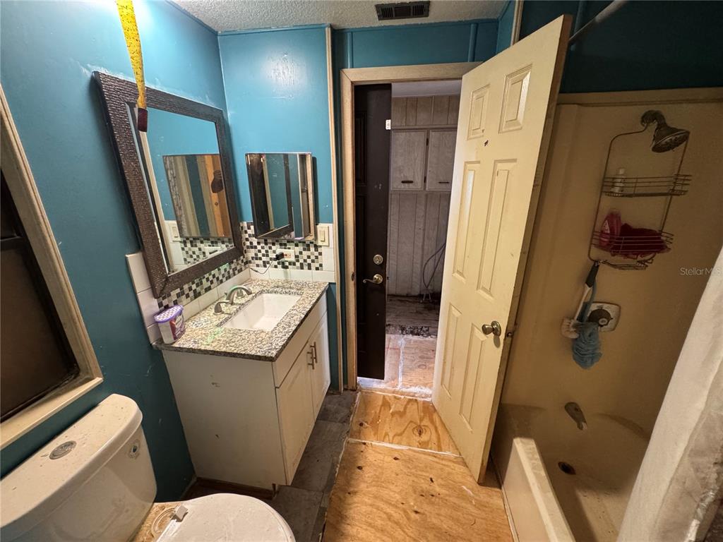 A bathroom features a vanity, toilet, shower, and an open doorway leading to another room — 10559 BAY HILLS CIRCLE, THONOTOSASSA, FL