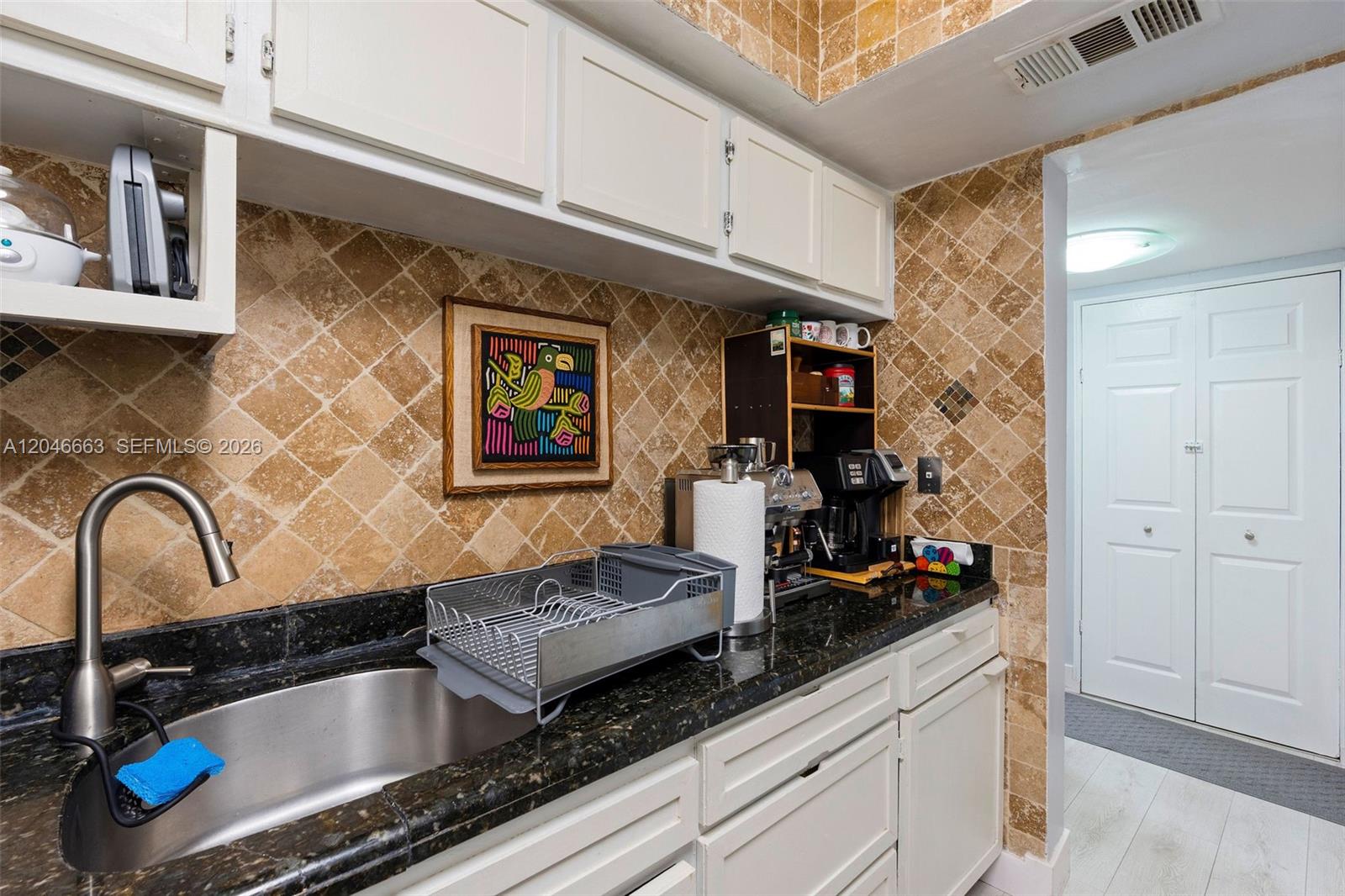 A kitchen features white cabinets, dark granite countertops, and a tan tiled backsplash — 2075 SW 122nd Ave # 505, Miami FL 33175, MIAMI, FL