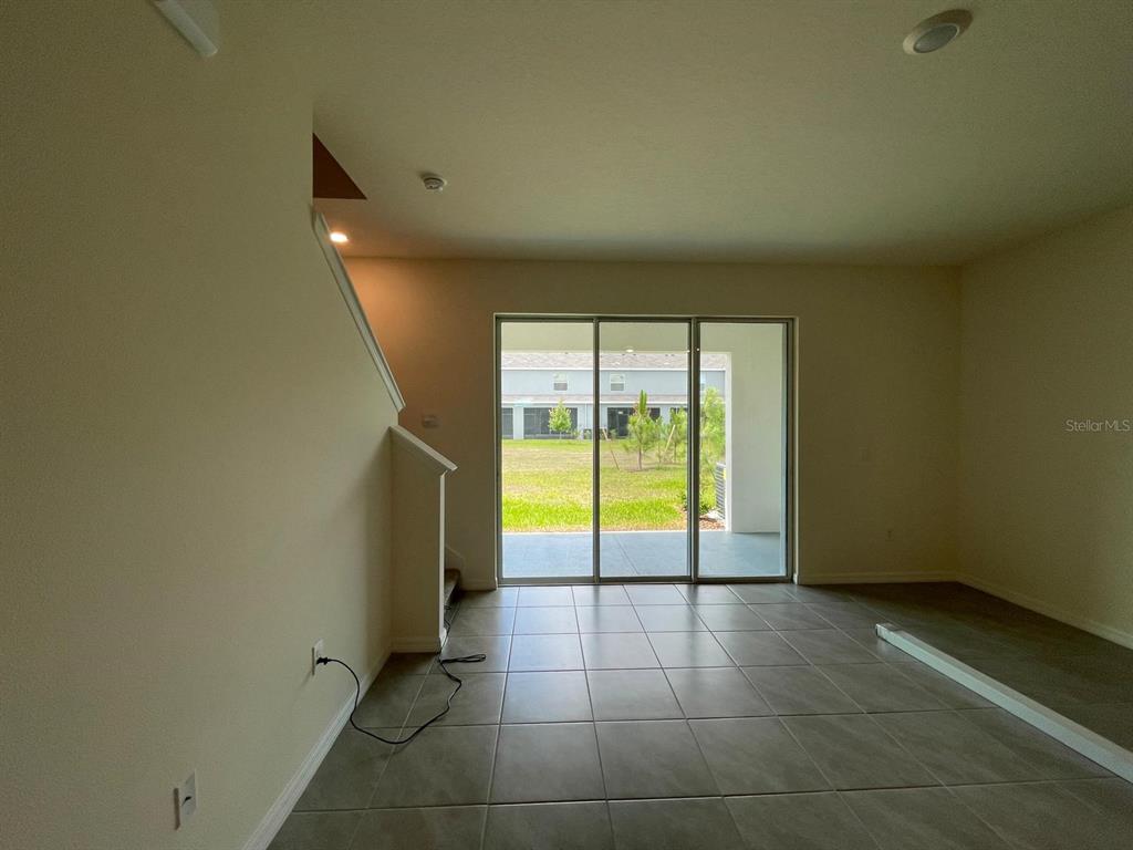 A room with tile flooring and a sliding glass door leading to a grassy backyard — 32930 REGENT CANAL STREET, WESLEY CHAPEL, FL