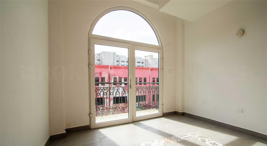 An empty room with tile flooring features a large arched glass door opening to a balcony — 319 RECINTO SUR STREET UNIT 6, SAN JUAN, PR