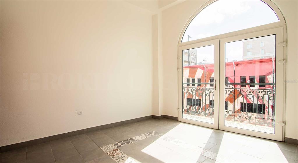 An empty room with gray tile flooring and a large arched glass door leading outside — 319 RECINTO SUR STREET UNIT 6, SAN JUAN, PR