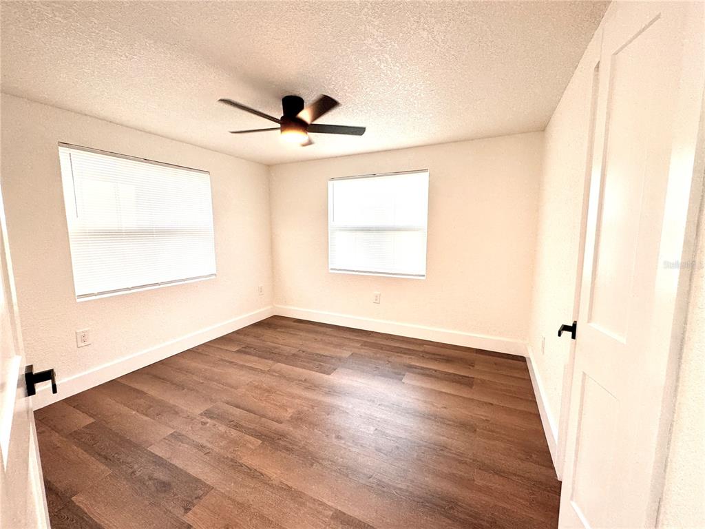 An open-concept living area features light wood flooring, white walls, and a modern kitchen island — 1135 CHEROKEE DRIVE, KISSIMMEE, FL
