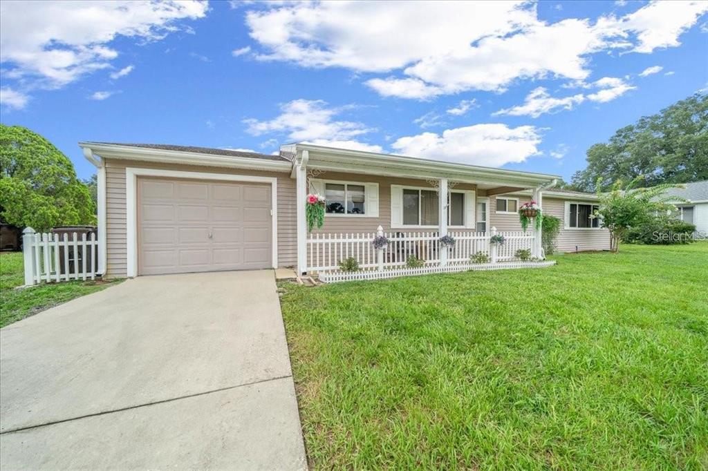 A single-story house with beige siding, a garage, and a white picket fence — 10820 SW 87TH TERRACE, OCALA, FL