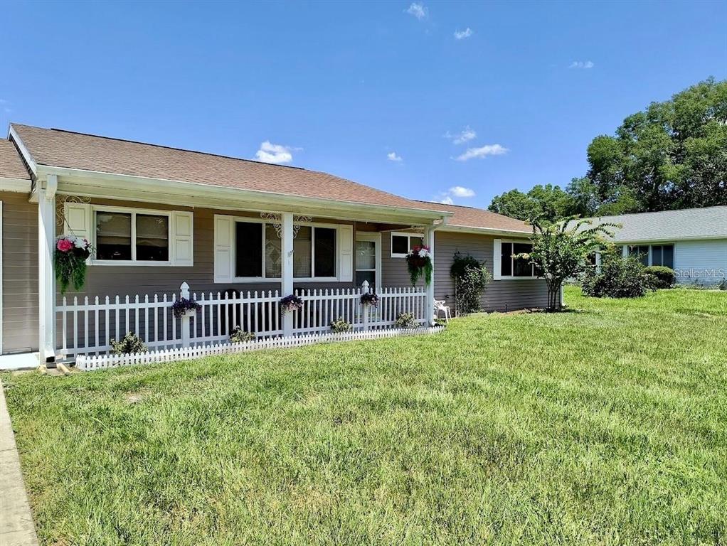 A single-story house with tan siding, a white picket fence, and a grassy front yard — 10820 SW 87TH TERRACE, OCALA, FL