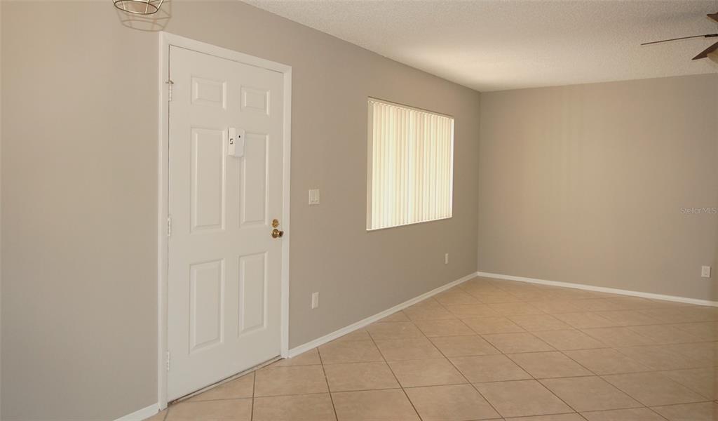 An interior view of a room with beige walls, tile flooring, and a white door — 3300 FOX CHASE CIRCLE N UNIT 216, PALM HARBOR, FL
