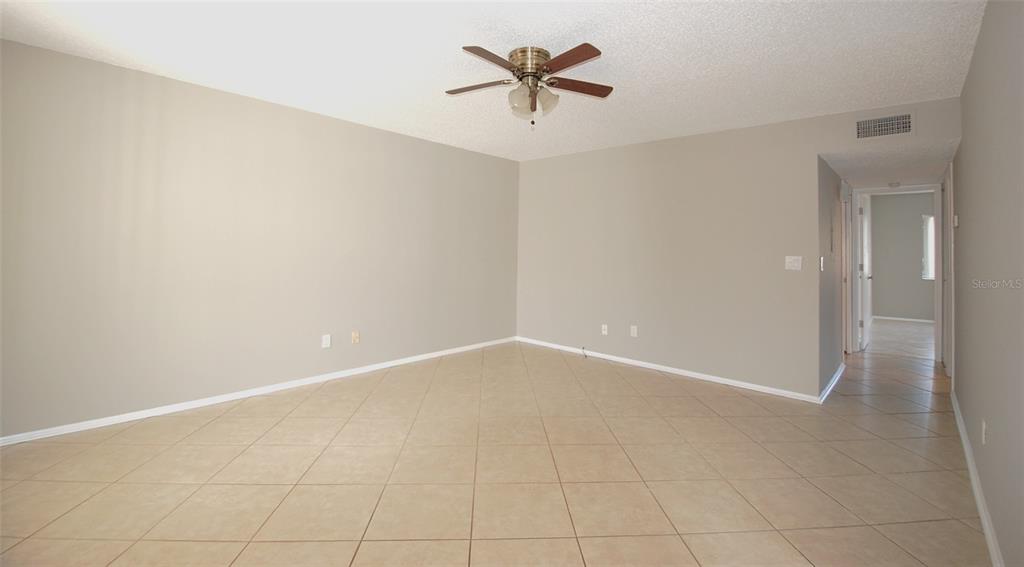 An empty room with beige walls, a ceiling fan, and light-colored tile flooring — 3300 FOX CHASE CIRCLE N UNIT 216, PALM HARBOR, FL