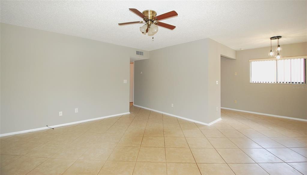 An empty room with beige tile flooring, light gray walls, and a ceiling fan — 3300 FOX CHASE CIRCLE N UNIT 216, PALM HARBOR, FL