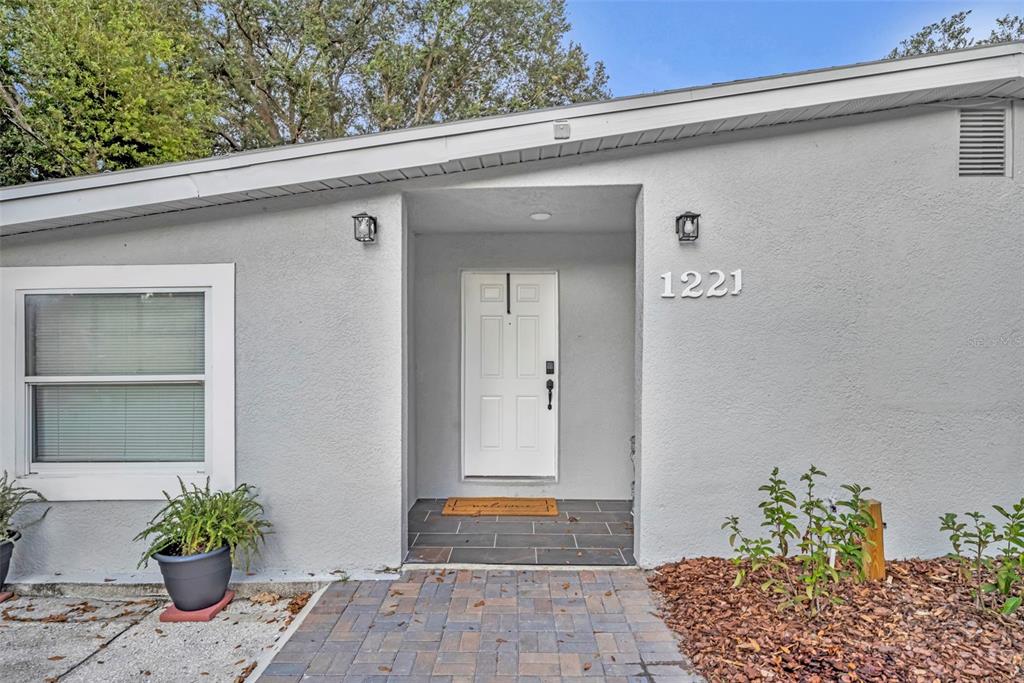 A single-story house with a light gray exterior, white trim, and a gravel front yard — 1221 ELINORE DRIVE, ORLANDO, FL