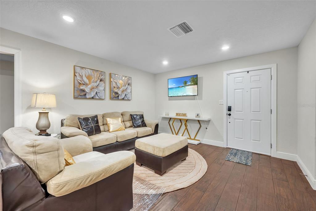 A living room with tile floors, a beige sofa set, and an open kitchen area — 1221 ELINORE DRIVE, ORLANDO, FL