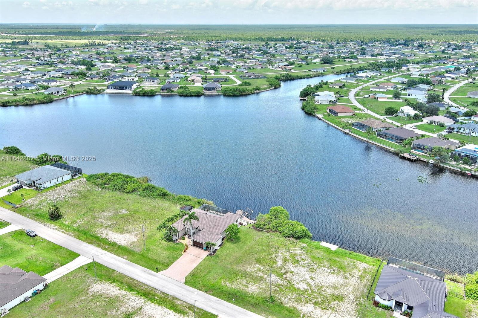 An aerial view shows a house with a pool situated on a waterfront lot — 401 NW 24th Ter, Cape Coral FL 33993, CAPE CORAL, FL