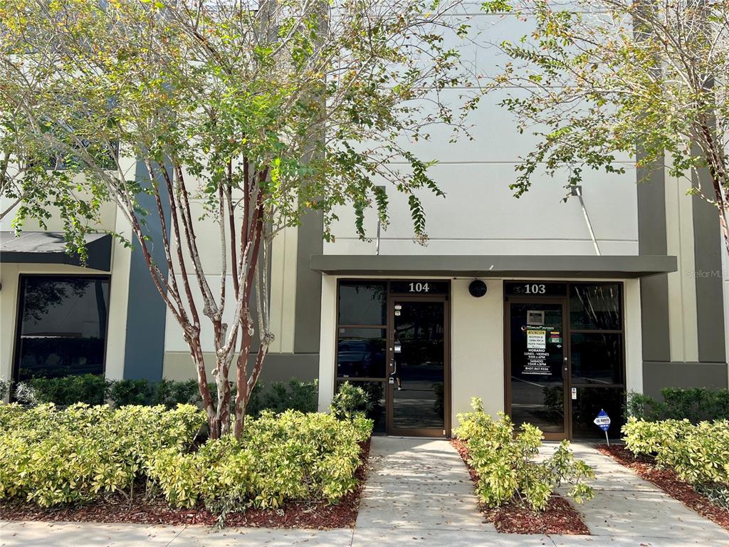The exterior of a commercial building features two glass entry doors labeled 104 and 103 — 8600 COMMODITY CIRCLE UNIT 104, ORLANDO, FL