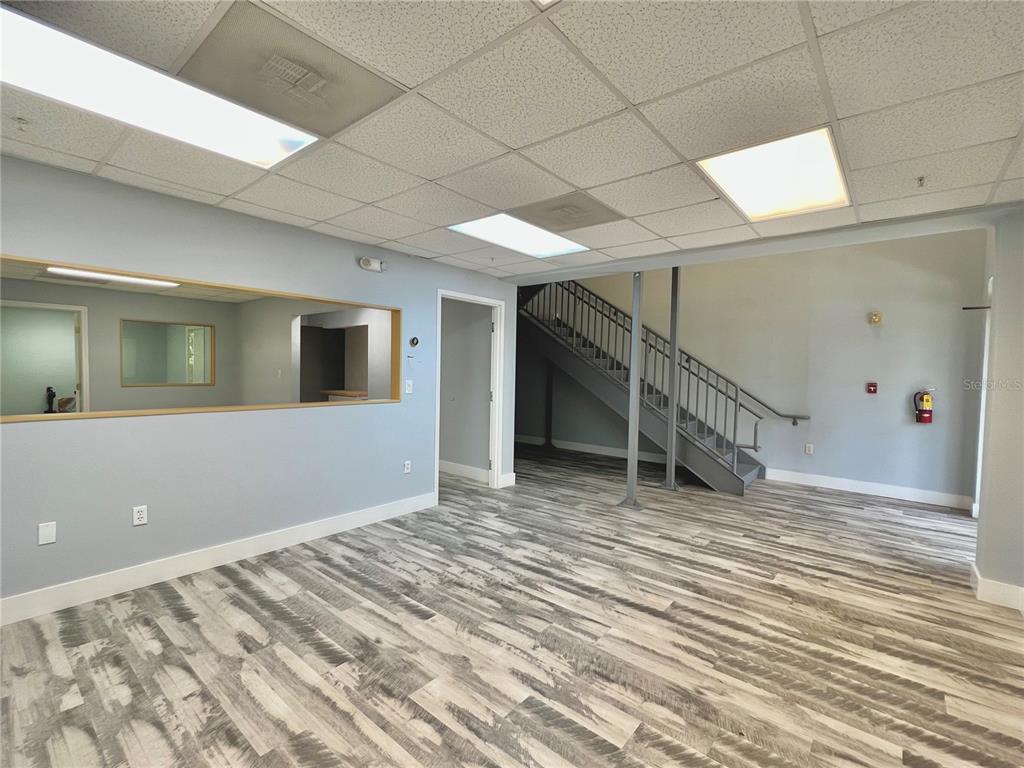 An office space features gray walls, wood-look flooring, a drop ceiling, and an open staircase — 8600 COMMODITY CIRCLE UNIT 104, ORLANDO, FL