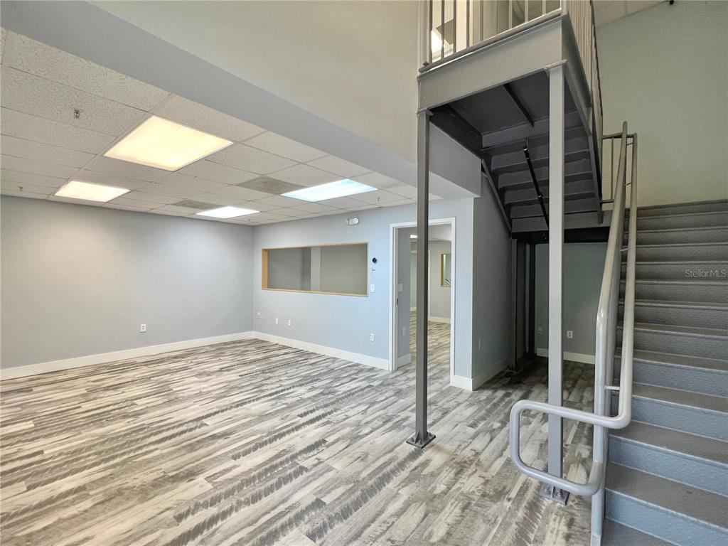 An office space features light blue walls, wood-look flooring, a drop ceiling, and metal stairs — 8600 COMMODITY CIRCLE UNIT 104, ORLANDO, FL