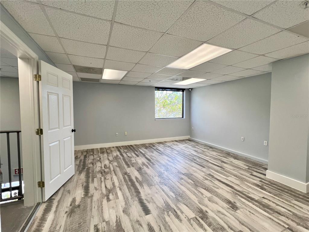 An empty office with light gray walls, wood-look flooring, and a drop ceiling — 8600 COMMODITY CIRCLE UNIT 104, ORLANDO, FL
