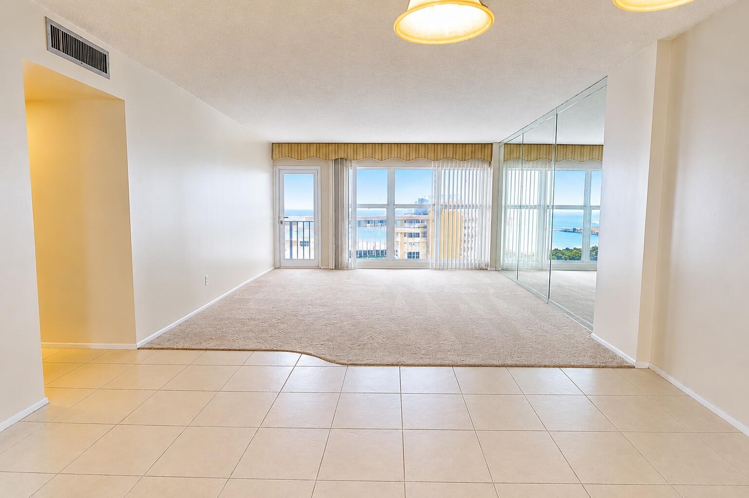 A living room features a blue sofa, matching armchair, mirrored walls, and a television console — 405 N Ocean Boulevard # 1704, Pompano Beach FL 33062, POMPANO BEACH, FL